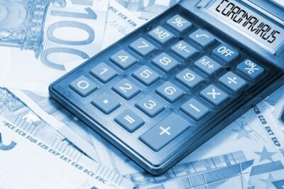 Calculadora sobre fondo de billetes mostrando el texto coronavirus en su pantalla